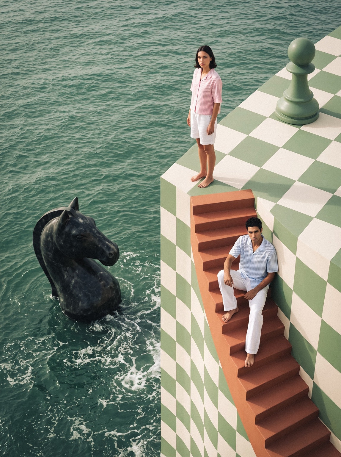 Pawn Up models on a chess platform beside the sea